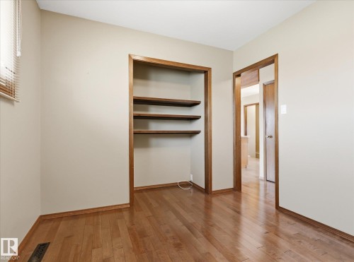 Room featuring wood-finish flooring, built-in shelving, and light neutral wall tones - 13504 116 St Nw, Edmonton, AB - Indoor Photo Showing Other Room
