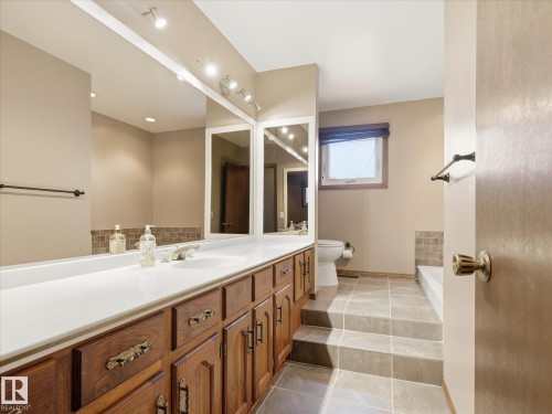 Bathroom featuring an extended vanity with wood-finish cabinetry and a white countertop - 13504 116 St Nw, Edmonton, AB - Indoor Photo Showing Bathroom