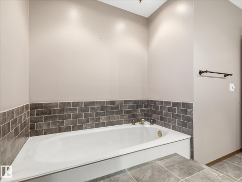 Soaking tub with gold-finish fixtures and subway tile surround - 13504 116 St Nw, Edmonton, AB - Indoor Photo Showing Bathroom
