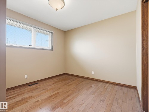 Interior room featuring wood-finish flooring, neutral wall paint, and a white ceiling with a flush-mount light fixture - 13504 116 St Nw, Edmonton, AB - Indoor Photo Showing Other Room