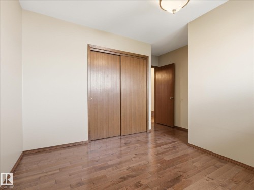 Bedroom featuring light-toned walls, wood-finish flooring, and a flush-mount ceiling light fixture - 13504 116 St Nw, Edmonton, AB - Indoor Photo Showing Other Room