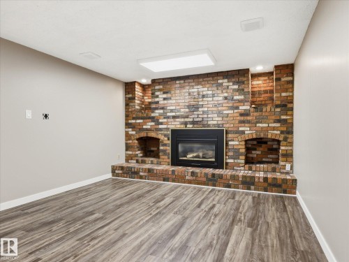 Brick fireplace with an integrated firebox and hearth, flanked by arched alcoves - 13504 116 St Nw, Edmonton, AB - Indoor With Fireplace