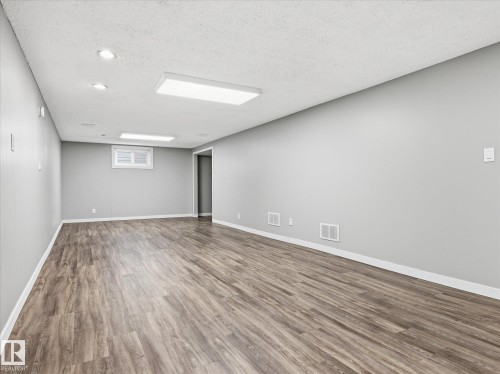 Expansive room featuring wood-finish flooring, light gray walls, and white baseboards - 13504 116 St Nw, Edmonton, AB - Indoor