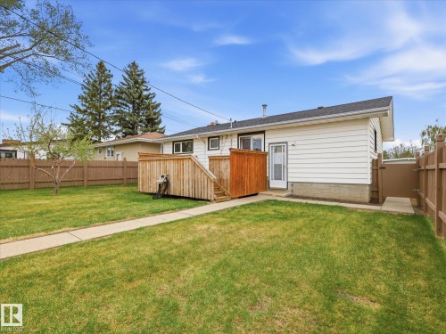 Expansive backyard featuring a lush lawn, wooden privacy fencing, and a multi-level wooden deck with privacy screen - 13504 116 St Nw, Edmonton, AB - Outdoor