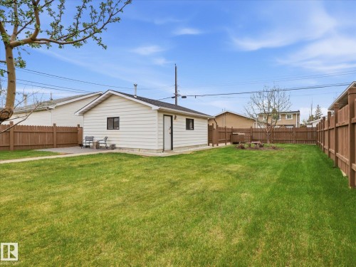 Expansive rear yard featuring a detached auxiliary structure, full wood fencing, a stone patio area, and mature trees - 13504 116 St Nw, Edmonton, AB - Outdoor