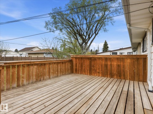 Spacious outdoor deck with natural wood planking and a high privacy fence - 13504 116 St Nw, Edmonton, AB - Outdoor With Exterior