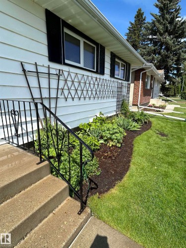White siding exterior with black window shutters and a decorative trellis - 13504 116 St Nw, Edmonton, AB - Outdoor