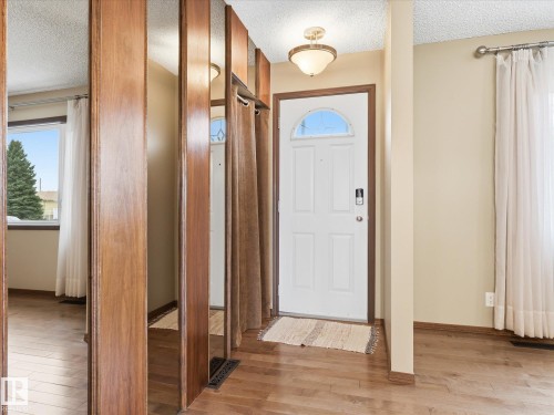 Front entry featuring a white door with an arched window, wood-finish flooring, and a semi-flush ceiling light fixture - 13504 116 St Nw, Edmonton, AB - Indoor Photo Showing Other Room