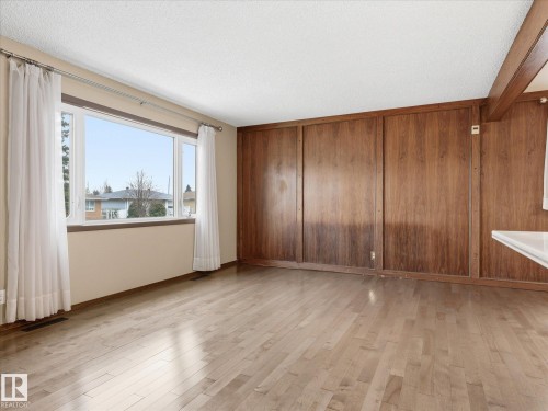 Expansive room featuring hardwood flooring, a large multi-pane window, and full-height wood paneling - 13504 116 St Nw, Edmonton, AB - Indoor Photo Showing Other Room