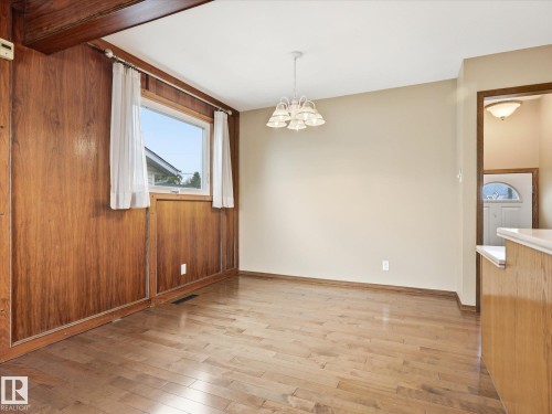 Room featuring wood-finish flooring, a wood-paneled accent wall, and a multi-light chandelier - 13504 116 St Nw, Edmonton, AB - Indoor Photo Showing Other Room