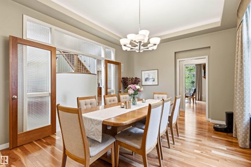 Dining area featuring wood-finish flooring, a tray ceiling, and a contemporary chandelier - 1728 Rutherford Pt Point(E) Sw, Edmonton, AB - Indoor Photo Showing Dining Room