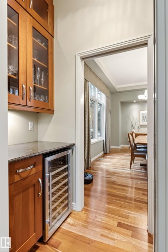 Custom built-in cabinetry with glass-front uppers and a built-in wine refrigerator, complemented by a stone-finish countertop - 1728 Rutherford Pt Point(E) Sw, Edmonton, AB - Indoor