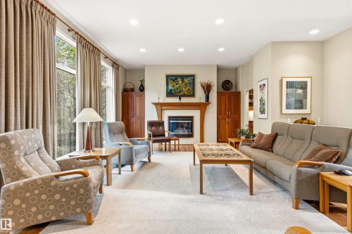 Spacious living area featuring a fireplace with a wood mantle, recessed lighting, expansive windows, and light-toned wall finishes - 1728 Rutherford Pt Point(E) Sw, Edmonton, AB - Indoor Photo Showing Living Room With Fireplace