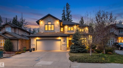 Contemporary stone and stucco exterior featuring a two-car garage, dark-framed windows, and an illuminated entryway - 1728 Rutherford Pt Point(E) Sw, Edmonton, AB - Outdoor With Facade