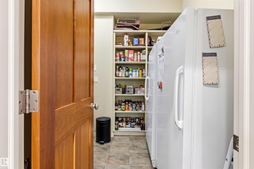 Dedicated pantry space featuring built-in shelving, two full-sized white refrigerators, and tile flooring - 1728 Rutherford Pt Point(E) Sw, Edmonton, AB - Indoor