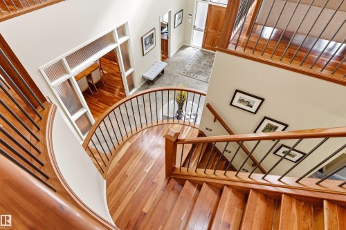 Grand spiral staircase featuring hardwood treads and risers, wrought iron balusters, and a solid wood handrail - 1728 Rutherford Pt Point(E) Sw, Edmonton, AB - Indoor Photo Showing Other Room