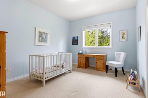 Light blue painted walls with white baseboards frame a window overlooking lush greenery - 1728 Rutherford Pt Point(E) Sw, Edmonton, AB - Indoor Photo Showing Bedroom