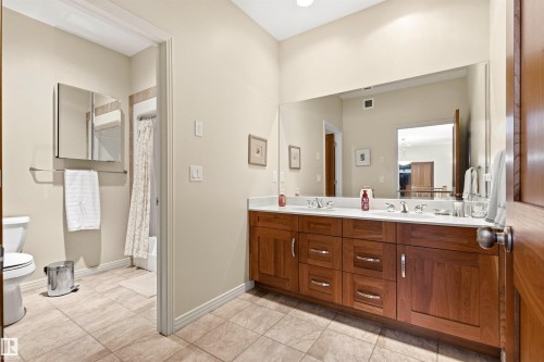 Dual vanity with wood-finish cabinetry, integrated sinks, and polished chrome fixtures - 1728 Rutherford Pt Point(E) Sw, Edmonton, AB - Indoor Photo Showing Bathroom