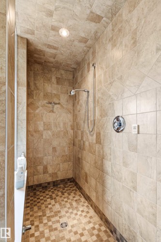 Tiled shower with a full-height tile surround, recessed lighting, and a built-in shower ledge - 1728 Rutherford Pt Point(E) Sw, Edmonton, AB - Indoor Photo Showing Bathroom