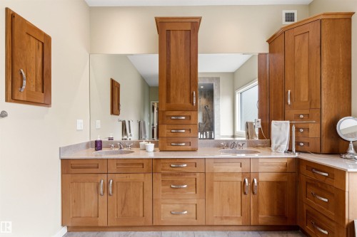 Dual vanity with integrated sinks, ample wood-finish cabinetry, and expansive mirror - 1728 Rutherford Pt Point(E) Sw, Edmonton, AB - Indoor Photo Showing Bathroom