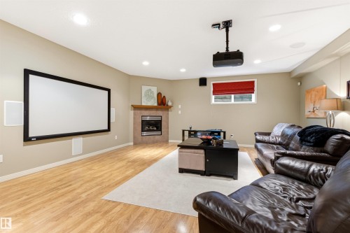 Entertainment room featuring a large projection screen, recessed lighting, and wood-finish flooring - 1728 Rutherford Pt Point(E) Sw, Edmonton, AB - Indoor With Fireplace