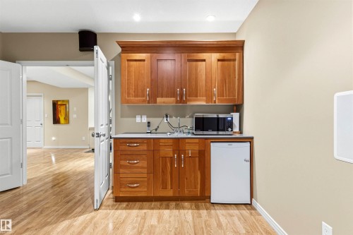Wet bar featuring wood cabinetry, a built-in sink, solid surface countertop, and recessed lighting - 1728 Rutherford Pt Point(E) Sw, Edmonton, AB - Indoor Photo Showing Kitchen