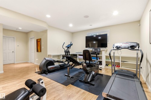 Versatile recreational room featuring wood-finish flooring, recessed lighting, and a window with natural light - 1728 Rutherford Pt Point(E) Sw, Edmonton, AB - Indoor Photo Showing Gym Room