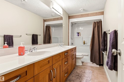Double vanity with white countertop, chrome fixtures, and wood-finish cabinetry - 1728 Rutherford Pt Point(E) Sw, Edmonton, AB - Indoor Photo Showing Bathroom