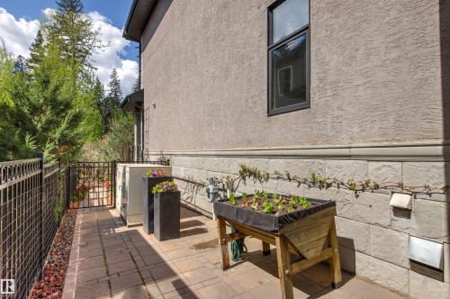 Paved patio area featuring a wrought iron fence and gate, stucco exterior, and stone veneer foundation - 1728 Rutherford Pt Point(E) Sw, Edmonton, AB - Outdoor With Exterior