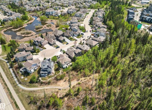 Expansive aerial overview showcasing a residential community featuring mature trees, a natural pond with islands, and varied architectural styles - 1728 Rutherford Pt Point(E) Sw, Edmonton, AB - Outdoor With View