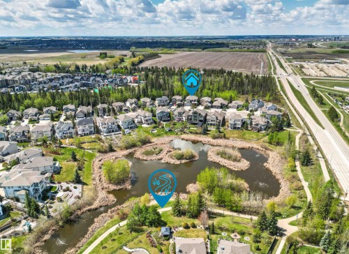 Aerial perspective showcasing a residential neighborhood with varied home styles, a central pond feature, and surrounding green spaces - 1728 Rutherford Pt Point(E) Sw, Edmonton, AB - Outdoor With View