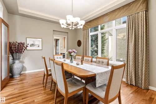 Dining area featuring wood-finish flooring, a large multi-pane window, and a tray ceiling - 1728 Rutherford Pt Point(E) Sw, Edmonton, AB - Indoor Photo Showing Dining Room