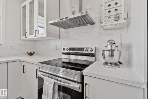 The kitchen features white cabinetry with bronze hardware, white countertops, and a white marble-patterned backsplash - 336 Southfork Drive, Leduc, AB - Indoor Photo Showing Kitchen