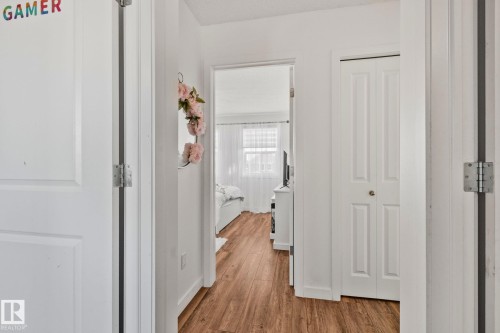 Hallway with wood-style flooring and white walls, leading to a room with a window - 336 Southfork Drive, Leduc, AB - Indoor