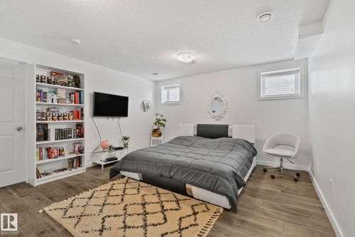 Bedroom featuring light wood-style flooring, a white wardrobe, and two windows with blinds - 336 Southfork Drive, Leduc, AB - Indoor Photo Showing Bedroom