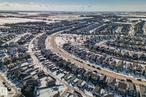 Aerial view of a residential neighbourhood featuring numerous detached properties with dark roofs, set against a backdrop of snow-covered fields - 336 Southfork Drive, Leduc, AB - Outdoor With View