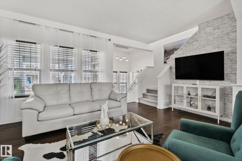 Living space featuring dark hardwood flooring, multiple windows with blinds, and a textured accent wall - 336 Southfork Drive, Leduc, AB - Indoor Photo Showing Living Room