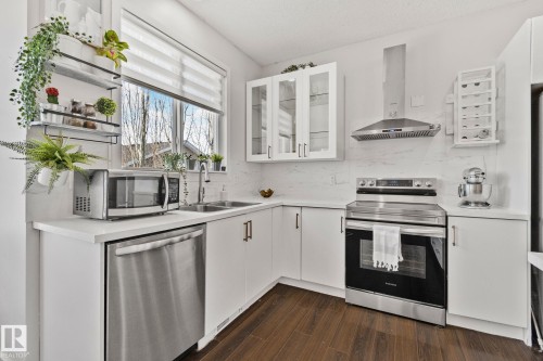 The kitchen features white cabinetry, stainless steel appliances including a range and dishwasher, and a double basin sink - 336 Southfork Drive, Leduc, AB - Indoor Photo Showing Kitchen With Double Sink With Upgraded Kitchen