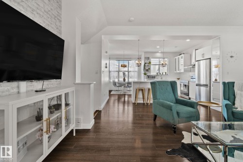 This inviting living area features dark wood-style flooring and light-colored walls, creating a bright and open atmosphere - 336 Southfork Drive, Leduc, AB - Indoor