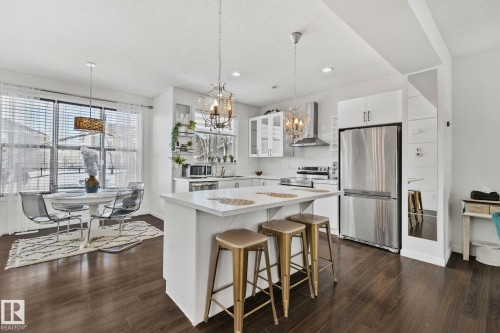 The property features a bright kitchen and dining area with dark wood flooring, white cabinetry, and stainless steel appliances - 336 Southfork Drive, Leduc, AB - Indoor Photo Showing Kitchen With Upgraded Kitchen