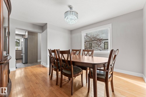 Dining area featuring hardwood floors, light gray walls, a window with white trim, and a chandelier - 10673 161 Avenue, Edmonton, AB - Indoor Photo Showing Dining Room