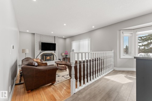 The living area features hardwood flooring, a white brick fireplace, and recessed lighting - 10673 161 Avenue, Edmonton, AB - Indoor With Fireplace