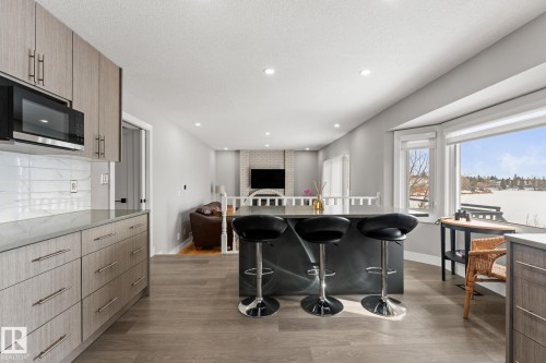The kitchen features wood-look cabinetry, a built-in microwave, and a kitchen island with bar seating - 10673 161 Avenue, Edmonton, AB - Indoor Photo Showing Kitchen With Upgraded Kitchen