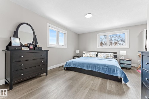 This spacious room features light grey walls, light-colored flooring, and two windows providing natural light - 10673 161 Avenue, Edmonton, AB - Indoor Photo Showing Bedroom