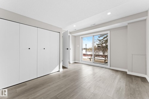 This room features light-colored plank flooring, recessed lighting, and a sliding glass door providing outdoor views - 10673 161 Avenue, Edmonton, AB - Indoor