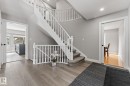 The property features a grand curved staircase with white balusters and carpeted treads, complemented by light grey walls and wide plank flooring - 10673 161 Avenue, Edmonton, AB  - Indoor Photo Showing Other Room 
