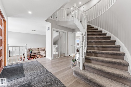 The property features a grand curved staircase with carpeted treads and white railings, complemented by light-colored flooring - 10673 161 Avenue, Edmonton, AB - Indoor Photo Showing Other Room