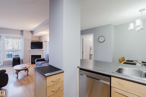 Kitchen area featuring a stainless steel dishwasher, undermount sink, and light wood cabinetry - 508 11103 84 Avenue, Edmonton, AB - Indoor Photo Showing Kitchen With Fireplace