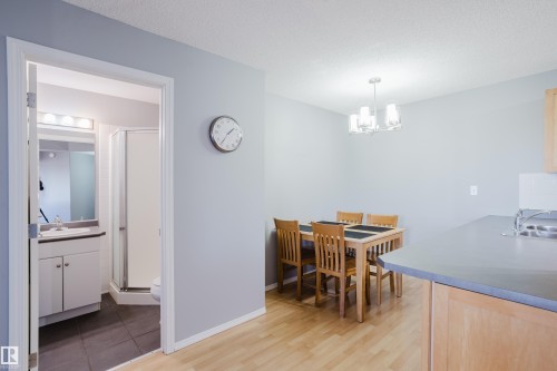 Open-concept living space featuring wood-finish flooring, a contemporary chandelier, and light gray wall tones - 508 11103 84 Avenue, Edmonton, AB - Indoor