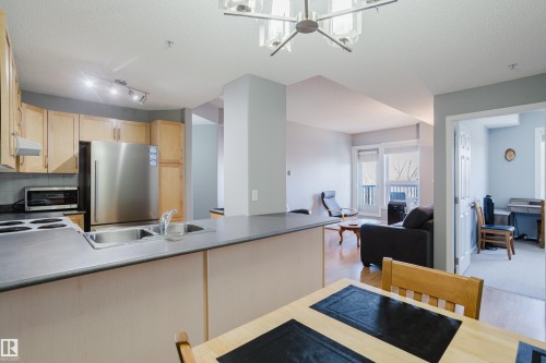 Open-concept kitchen featuring light wood cabinetry, stainless steel appliances, and a double basin sink - 508 11103 84 Avenue, Edmonton, AB - Indoor Photo Showing Kitchen With Double Sink